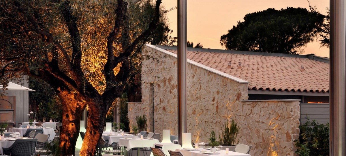 Dinieren Sie in entspannter, festlicher Atmosphäre umgeben von Olivenbäumen und Palmen und mit Blick auf den Pool